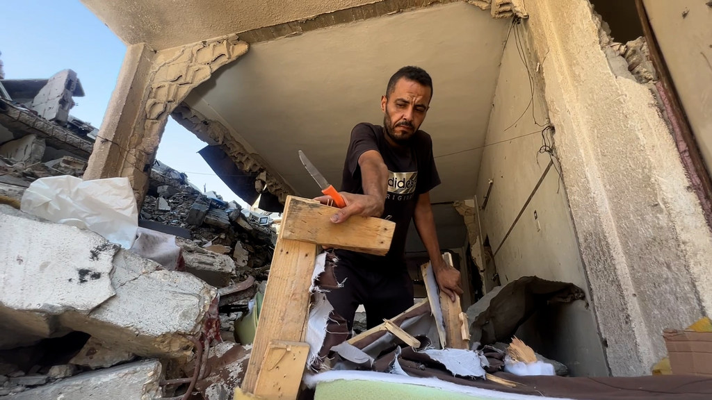 حسام ماضي، أحد سكان حي الشيخ رضوان شمال مدينة غزة، يقوم بإخراج بعض متعلقاته من منزله المدمر.